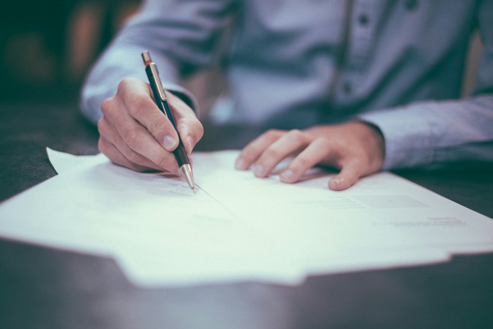A student writing notes on loose paper